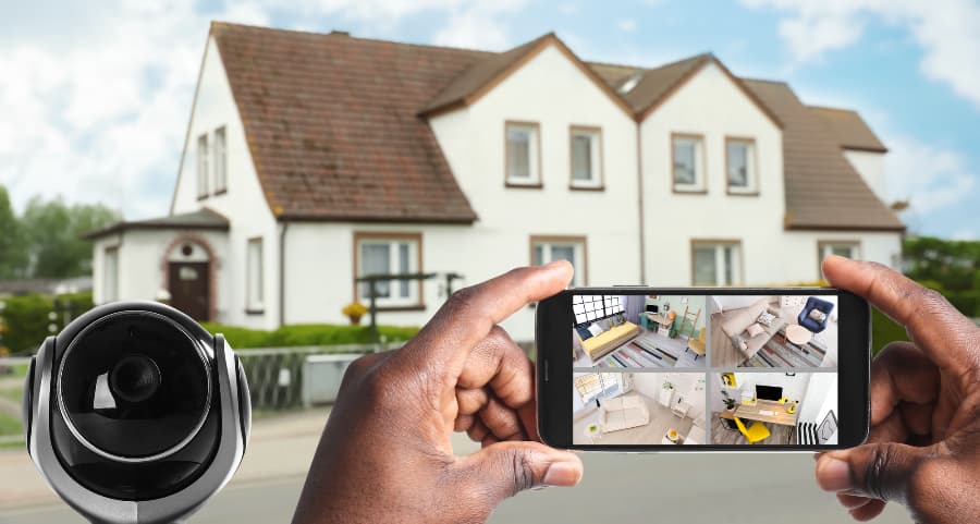 Man holding mobile device and viewing footage from video cameras