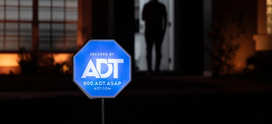 Blue ADT home security sign in front of a home at night.